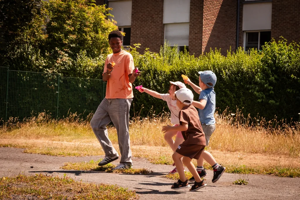 Un animateur s'amuse avec des enfants dehors