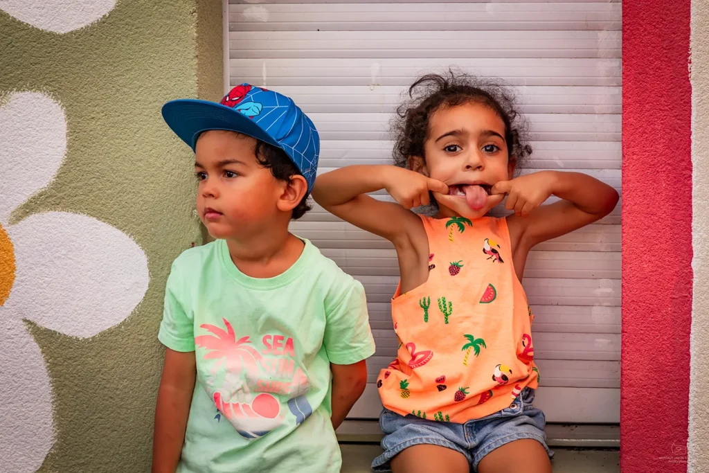 Deux enfants posent dans la cour de récréation de la maison de quartier Caramel. Une enfant fait une grimace