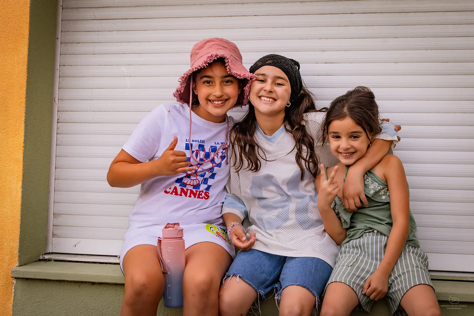 Trois petites filles posent ensemble dans la cour de récréation de la maison de quartier caramel
