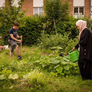 Deux personnes s'occupent des jardins en arrosant les plants