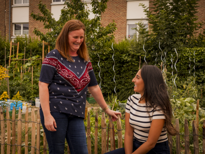 Deux adultes discutent dans les jardins de la maison de quartier Caramel