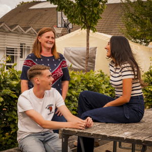 Trois adultes discutent dans les jardins de la maison de quartier Caramel